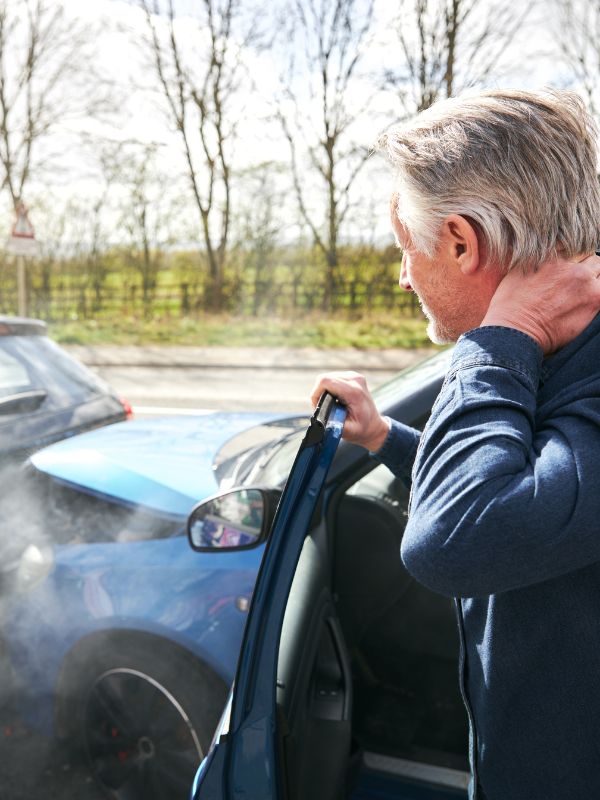 A man getting out of his car holding his neck after a DUI accident.