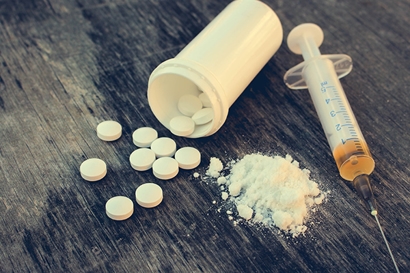 drugs prescription pill bottles and needles on a table