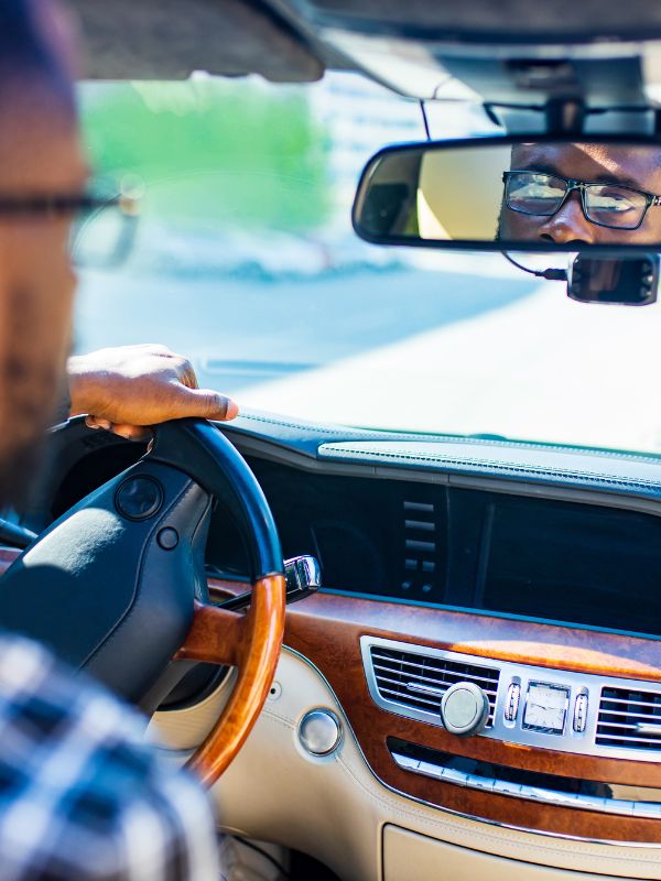 a man driving a car and looking in the backseat at his minor passenger