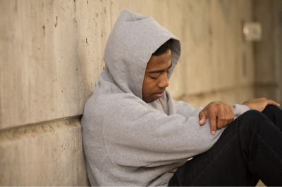 juvenile a man sitting on the ground leaning on a wall