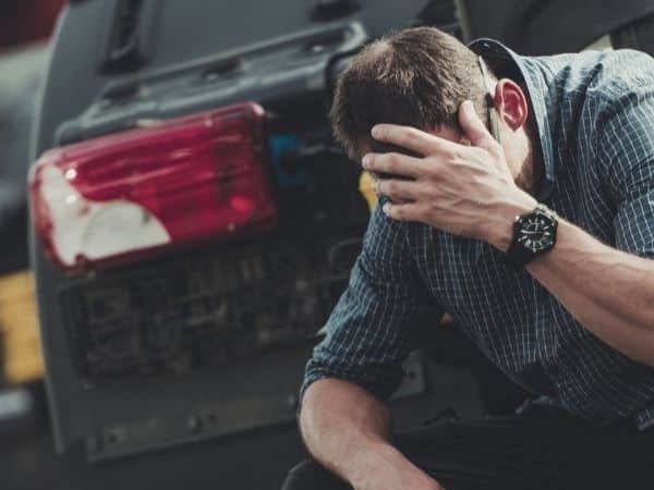 a man kneeling outside his car after a DUI